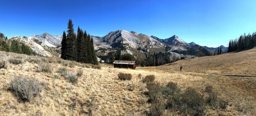 mountain and cabin panoramic view with hiker walking